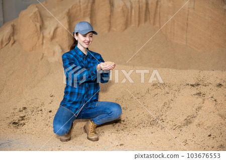 Farmer holding a handful of soybean husks in an animal feed warehouse 103676553