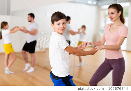 Cheerful woman practicing active dance in pair with tween son 103676844