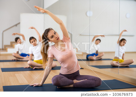 Woman sitting in lotus pose and stretching on family yoga training 103676973