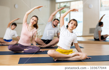 Family of four practicing yoga at gym Family of four practicing yoga at gym 103677044