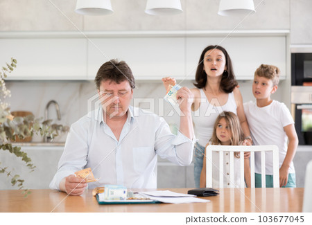 On kitchen table, father of family laid out financial documents and money banknotes. On kitchen table, father of family laid out financial documents and money banknotes. 103677045