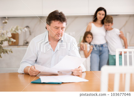 Wistful father looking through papers sitting in the kitchen Wistful father looking through papers sitting in the kitchen 103677046