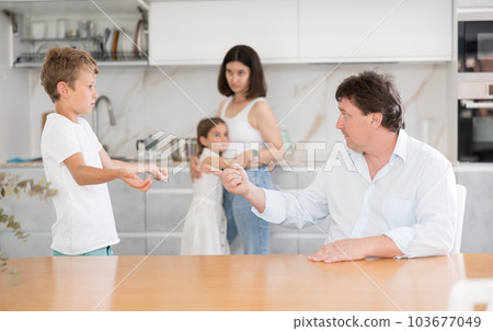 At home in kitchen, parents scold son for imprudent act committed At home in kitchen, parents scold son for imprudent act committed 103677049