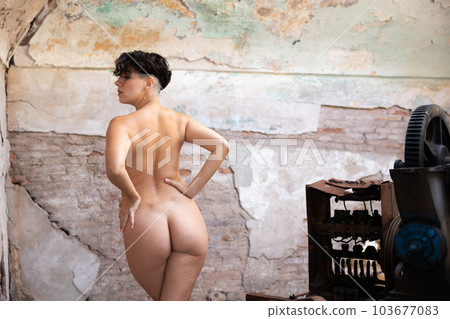 Absolutely naked sexy woman posing inside an old abandoned building. View from back Absolutely naked sexy woman posing inside an old abandoned building. View from back 103677083