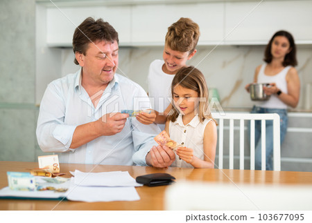 Happy father giving money to children in the kitchen 103677095