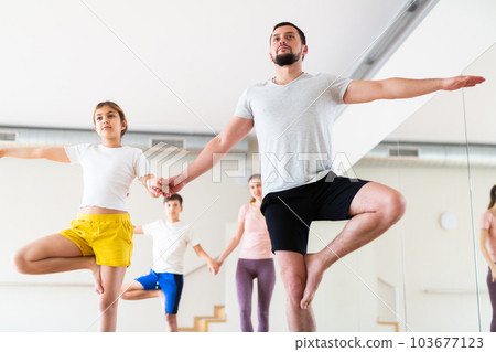 Family practicing partner yoga at studio 103677123