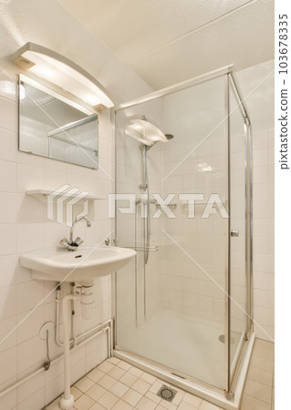a bathroom with a sink, mirror and shower stall in the corner area on the left side of the room 103678335