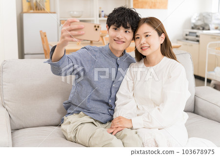 一對夫婦在他們的新房子裡用智能手機自拍 一對夫婦在他們的新房子裡用智能手機自拍 103678975