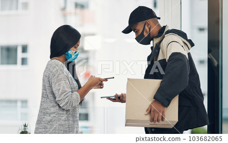 It just makes smarter sense to pay the contactless way. a masked young man and woman using smartphones during a home delivery. It just makes smarter sense to pay the contactless way. a masked young man and woman using smartphones during a home delivery. 103682065