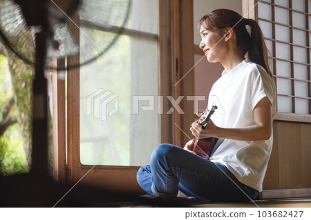 A woman playing an ukulele 103682427
