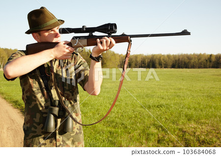 Hunter, gun and man in nature on a Africa safari for animal shooting with a weapon on vacation. Hunting sport, male person and target hunt practise of a traveler in camouflage looking at a scope Hunter, gun and man in nature on a Africa safari for animal shooting with a weapon on vacation. Hunting sport, male person and target hunt practise of a traveler in camouflage looking at a scope 103684068