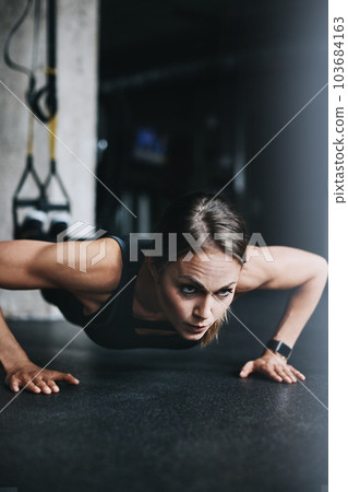 Fit is a lifestyle choice. an attractive young woman doing push ups in a gym. 103684163