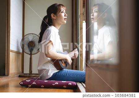 A woman playing an ukulele 103684381