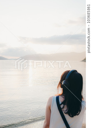 Woman wearing headphones looking at the sea 103685861