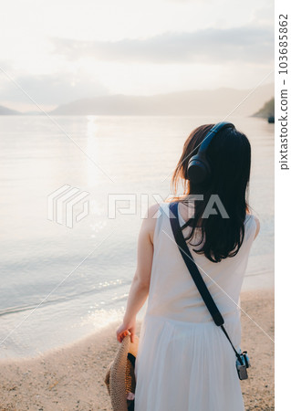 Woman wearing headphones looking at the sea Woman wearing headphones looking at the sea 103685862