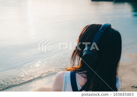 Woman wearing headphones looking at the sea 103685863