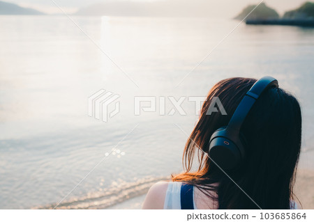 Woman wearing headphones looking at the sea Woman wearing headphones looking at the sea 103685864