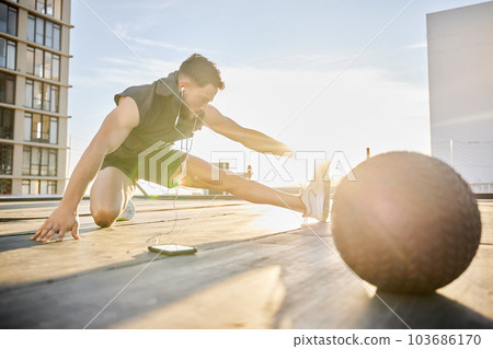 Im only getting warmed up. Shot of a sporty young man stretching while out on a rooftop. 103686170