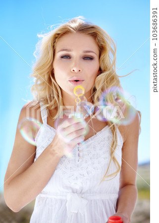 Summer, portrait and a woman blowing bubbles for happiness, fun and playful in nature. Beautiful, spring and a young lady with bubbles, playing and enjoying childlike energy in a garden or park 103686391