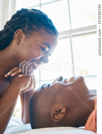 Happy african american couple laughing while looking into each others eyes. Couple sharing and intimate moment while bonding and spending time together at home 103686399