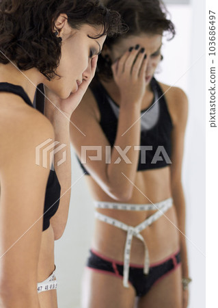 Measuring tape, woman and stress from diet, anorexia problem and upset mental health. Mirror, body and sad female person with eating disorder unhappy about reflection, weight and stomach measurements 103686497
