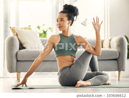 Yoga a day keeps the doctor away. Shot of a young woman practising yoga in her living room. 103686612