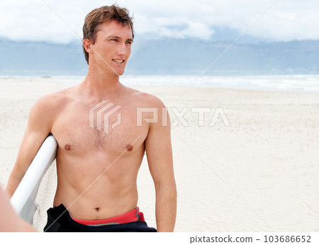 Surfing is a way of life. A young male surfer getting ready to go for a surf on a hot summers day. Surfing is a way of life. A young male surfer getting ready to go for a surf on a hot summers day. 103686652