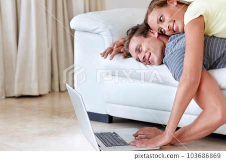 Could this be called online dating. A young woman lying on her boyfriends back as they both look at a laptop screen. Could this be called online dating. A young woman lying on her boyfriends back as they both look at a laptop screen. 103686869