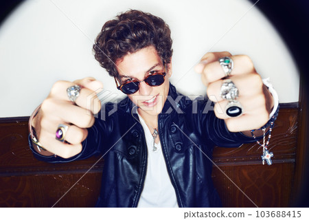 Awesome. Portrait of a stylish young man with both ring-clad fists pointed at the camera. 103688415
