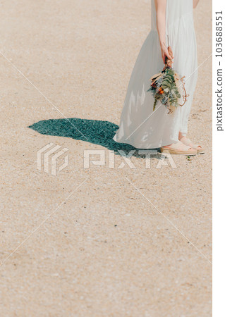 A woman standing with dried flowers on the beach A woman standing with dried flowers on the beach 103688551