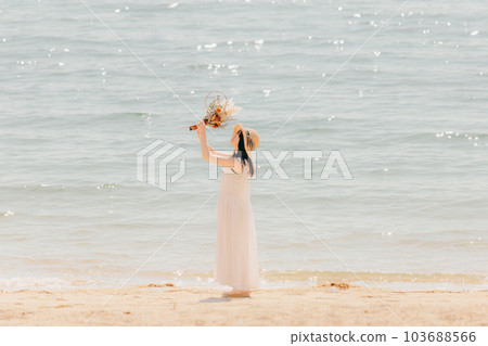 一個拿著乾花站在沙灘上的女人 一個拿著乾花站在沙灘上的女人 103688566