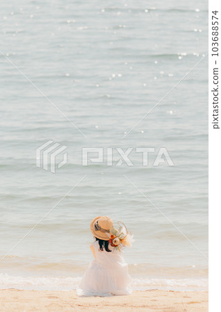 一個拿著乾花站在沙灘上的女人 103688574
