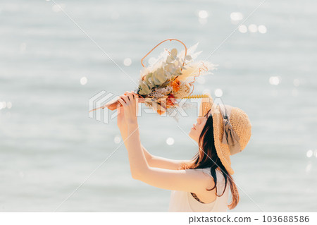 A woman standing with dried flowers on the beach 103688586