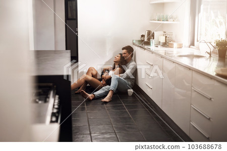 The familiar comforts of home. an affectionate young couple sitting on the kitchen floor. The familiar comforts of home. an affectionate young couple sitting on the kitchen floor. 103688678
