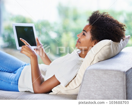 Getting in some online time. a young woman using a digital tablet while relaxing at home. 103688703