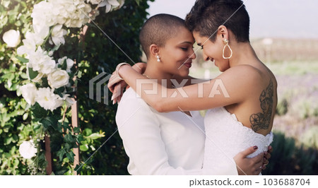They find happiness in each other. an affectionate young lesbian couple standing with their arms around each other on their wedding day. 103688704