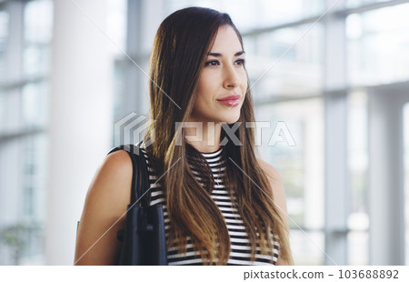 Shes got a plan and a purpose. a confident young businesswoman walking through a modern office. Shes got a plan and a purpose. a confident young businesswoman walking through a modern office. 103688892