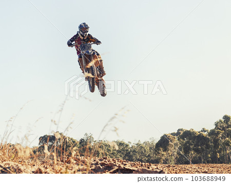 Ripping through the air. a motocross rider coming over a jump during a race. 103688949