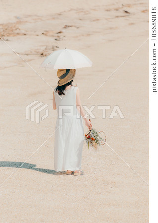 A woman holding a parasol and holding dried flowers A woman holding a parasol and holding dried flowers 103689018
