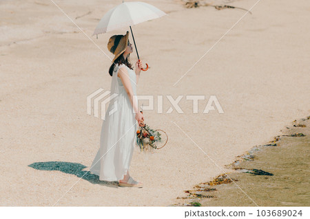 A woman holding a parasol and holding dried flowers 103689024