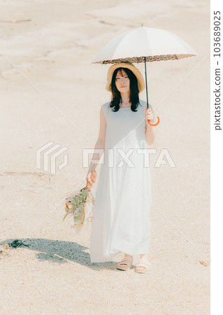 A woman holding a parasol and holding dried flowers 103689025