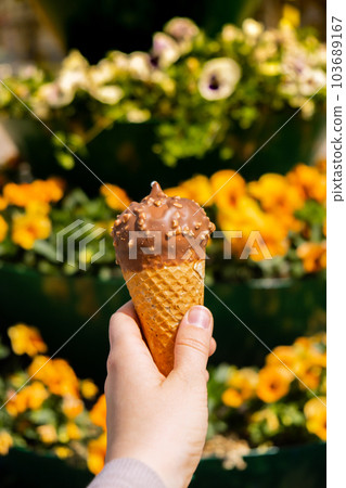 Female hand holding delicious american vanilla chocolate ice cream. Tasty homemade icecream Gelato in the waffle cone. Gluten free vegan dairy free 103689167