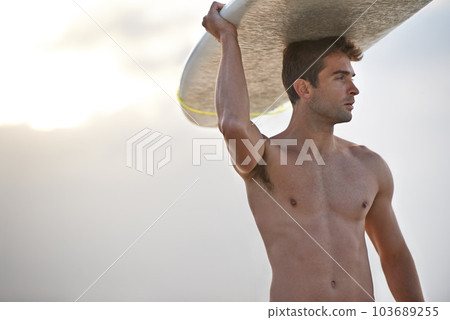 Chasing waves is his passion. A handsome young surfer at the beach craving a good wave. 103689255