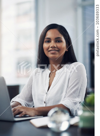 Success lies in the path of those who show dedication. Portrait of a young businesswoman working on a laptop in an office. 103689333