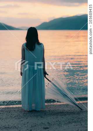 woman holding an umbrella in the sunset woman holding an umbrella in the sunset 103689435