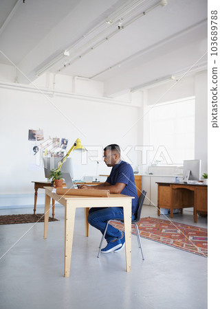 Creative, office or black man typing on laptop working on a blog project, digital or online research. Coworking, planning or focused African designer working on website in startup company agency Creative, office or black man typing on laptop working on a blog project, digital or online research. Coworking, planning or focused African designer working on website in startup company agency 103689788