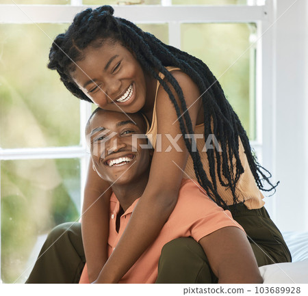 Young black african american couple smiling and laughing as they lovingly embrace in the bedroom at home. An affectionate good looking man and woman enjoying spending time together and looking in love 103689928