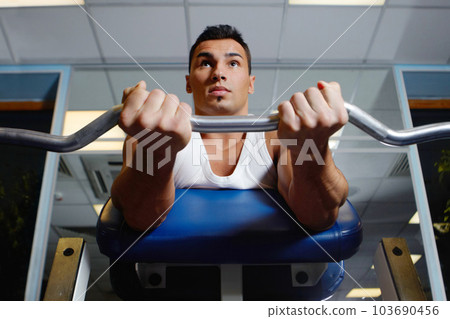 Gym bench, barbell exercise and man focus on muscle growth, strength training or lifting weights, curling or bodybuilding. Strong mindset, sports health and fitness person doing active workout 103690456