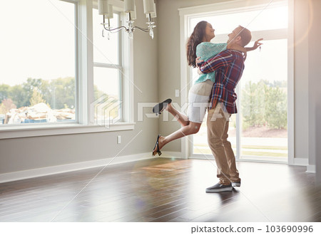 Happy couple, moving into their new home and hug for mortgage or property buy or together in empty lounge and romance. Real estate, man and woman excited or embrace and romance in the living room Happy couple, moving into their new home and hug for mortgage or property buy or together in empty lounge and romance. Real estate, man and woman excited or embrace and romance in the living room 103690996