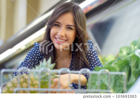 Shopping, grocery and smile with portrait of woman with trolley for supermarket, food and retail. Happy, food and product with female customer and cart in store for consumer, purchase and sale 103691083